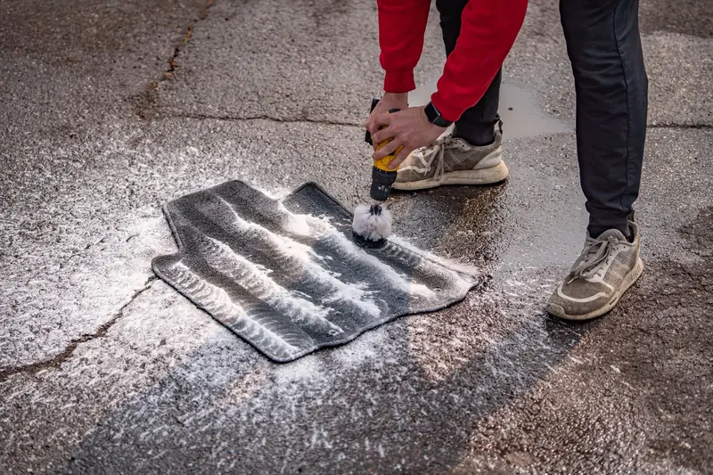 Cleaning floor mats in a driveway